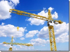 Construction cranes on sky background
